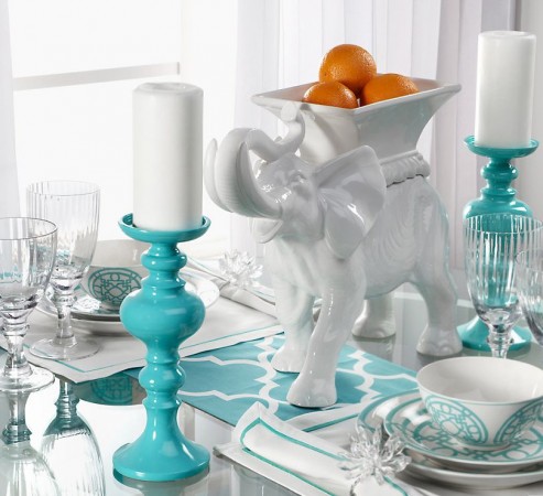 A table setting with a teal elephant and oranges, part of the 9 items every stylish home should have.