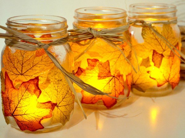 Three mason jars decorated with autumn leaves.