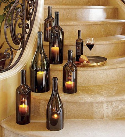 A group of wine bottles with candles on a staircase.