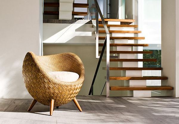A rattan chair in front of a staircase in an indoor space.