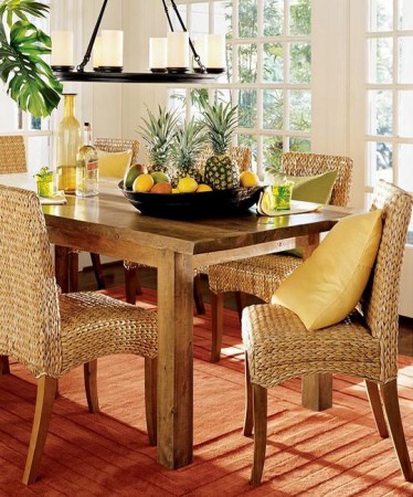 A dining room with rattan chairs and an orange rug.