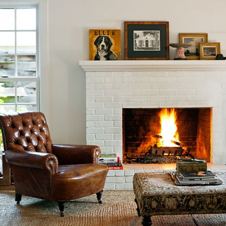 A stylish home should have a brown leather chair in front of a fireplace.