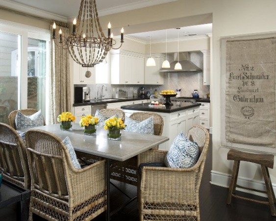 A white kitchen with rattan chairs and a chandelier.