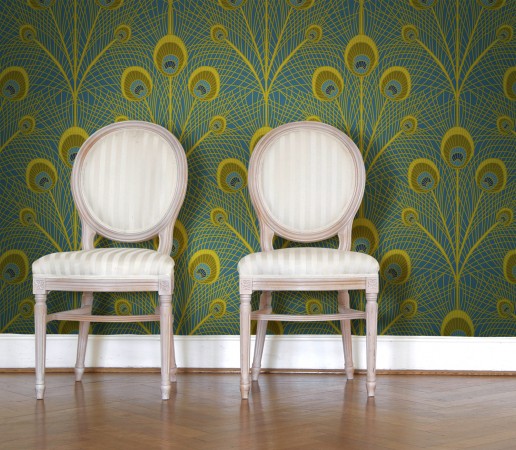 Two chairs in front of a peacock feather wallpaper.