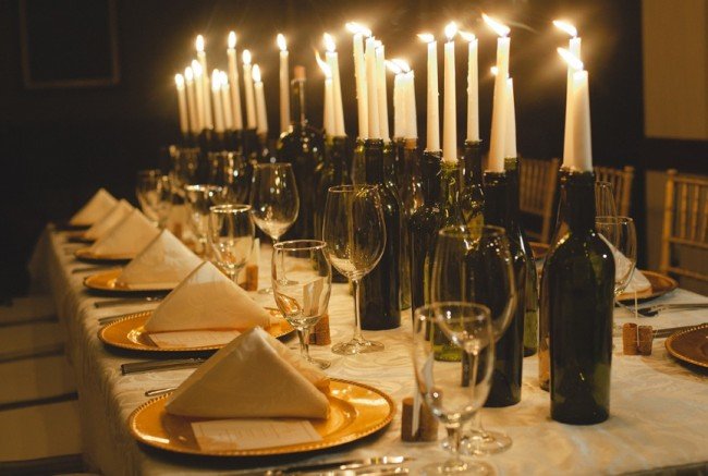 A decorating table adorned with candles and wine bottles.