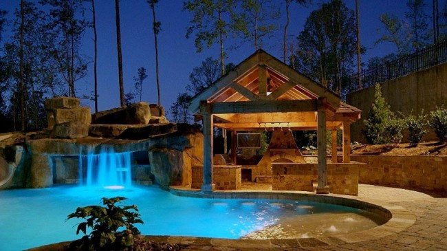 A swimming pool with waterfall is the centerpiece for this outdoor oasis