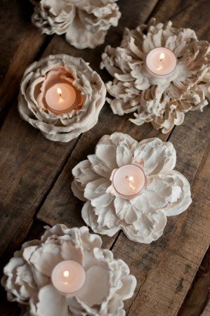 A group of white flower candle holders on a wooden table for decorating.