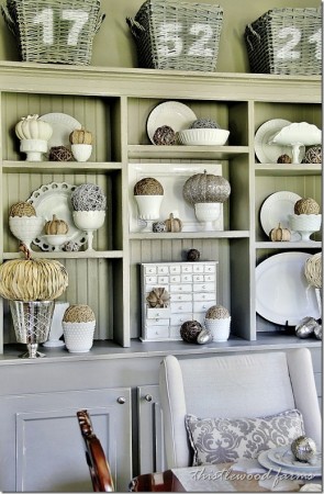 A stylish white hutch adorned with baskets and pumpkins, perfect for a stylish home.
