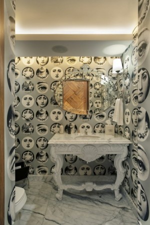 A stylish bathroom with black and white faces on the wall.