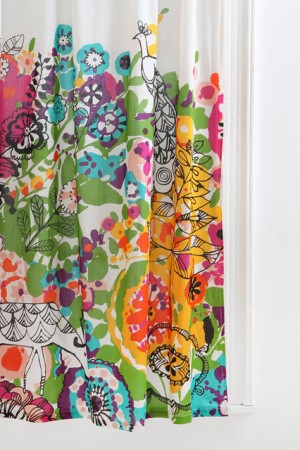 A watercolor design shower curtain hanging on a window.