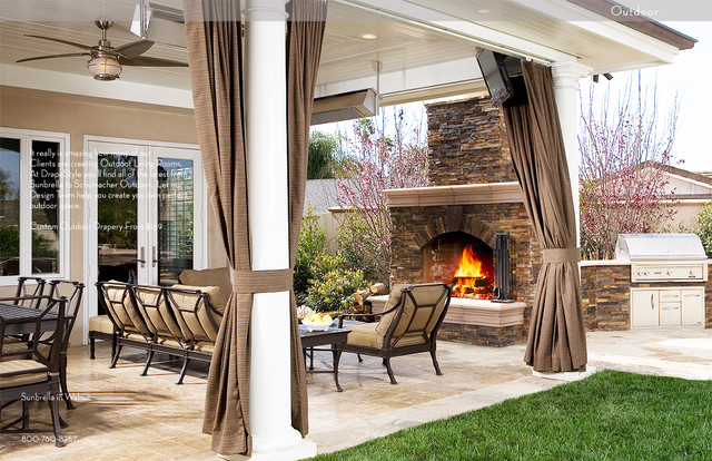 A covered patio with a fire place and curtains.