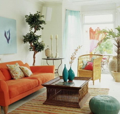 A living room with a bright orange rattan couch.