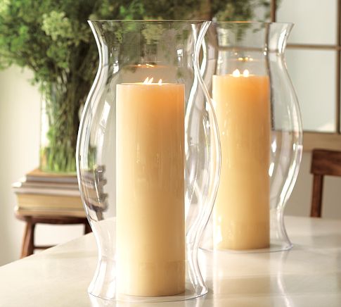 Two elegant glass vases beautifully decorated with candles on a table.