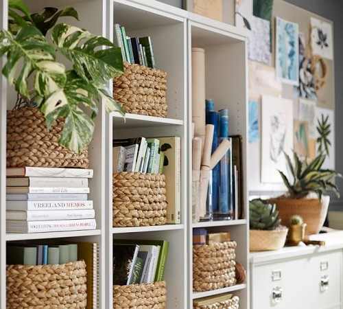 A stylish home with a white bookcase adorned with wicker baskets and plants.
