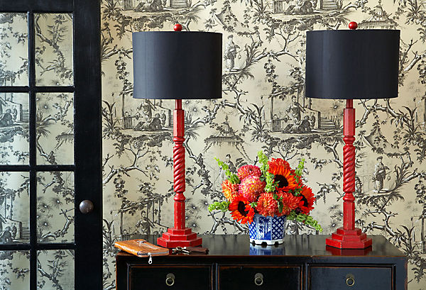 A stylish home with a dresser, lamps, and flowers.