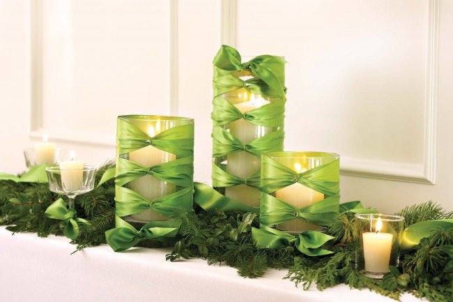 Three candles with green ribbons decorating a mantle.