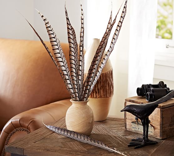 Pheasant feathers decoratively arranged in a vase, adding a touch of natural elegance to your nest-like table setting.