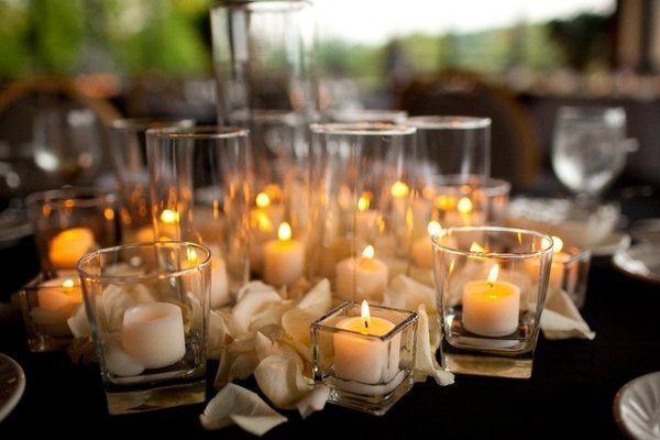 A decorative table with candles and white roses.