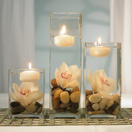 Glass vases with rocks and flowers display floating candles