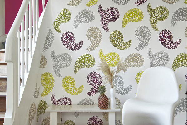 A chair in front of a paisley wallpaper.