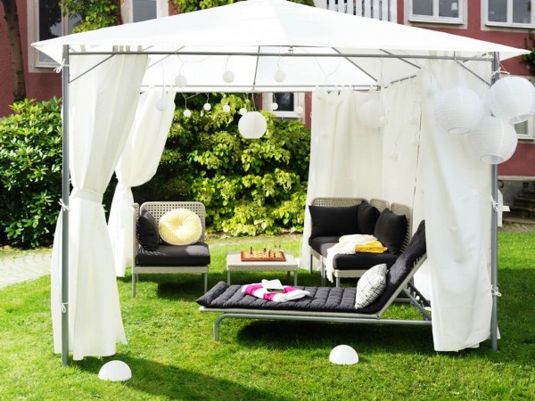 A white gazebo with a white canopy and black furniture.