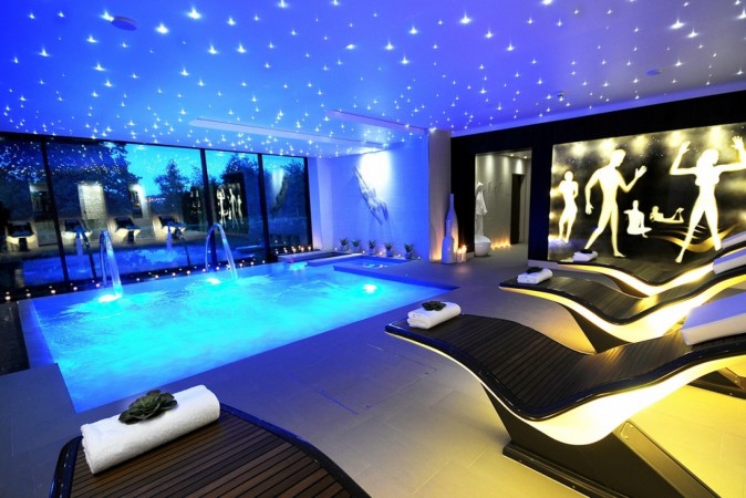 A large indoor swimming pool lit up with blue lights to inspire.