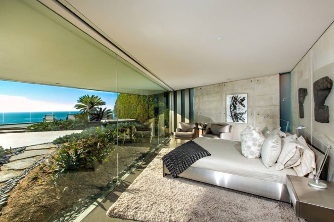 A splendid bedroom with a glass wall overlooking the ocean.