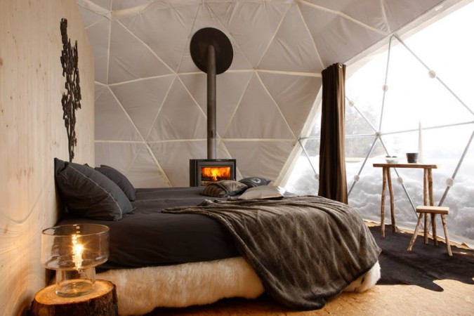 A cozy bed in an igloo with a fireplace in the middle that will give you a reason to redesign your room.