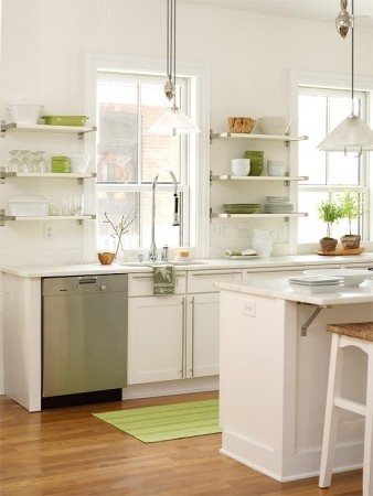 A white kitchen with open shelving and green stools.
