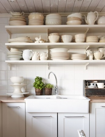 A white kitchen with open shelving filled with dishes.
