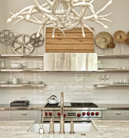An open shelving kitchen with antlers hanging from the ceiling.