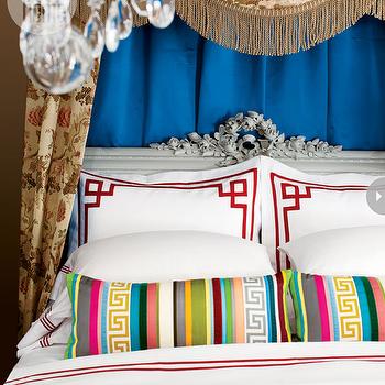 Colorful pillows and a chandelier accent a Greek Key design bed.