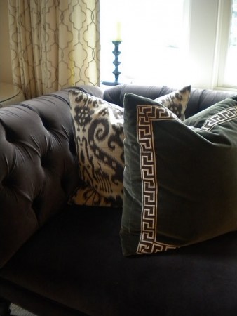 A black velvet couch with Greek Key Design pillows.