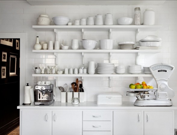 Open shelving in the white kitchen displays dishes and utensils.