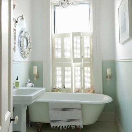 A pastel bathroom with a white bathtub and a chandelier.