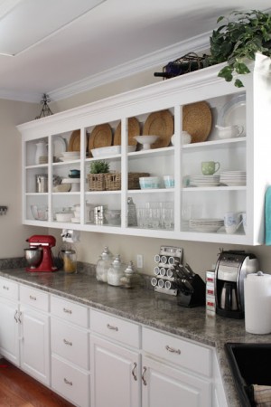A kitchen with white cabinets, counter tops, and open shelving.
