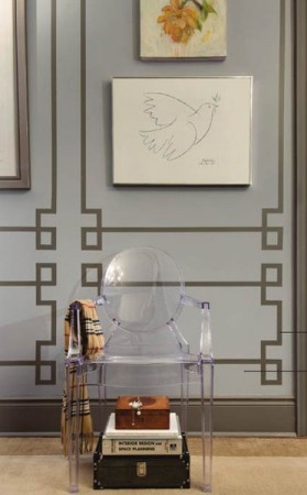 A clear chair with a Greek Key Design in a room with a painting on the wall.