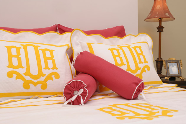 A bed with a personalized yellow and white comforter and pillows.