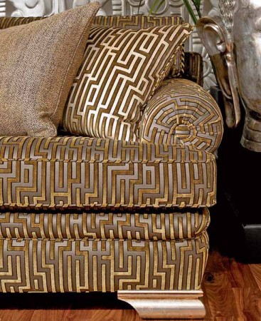 A Greek key design couch with decorative pillows and a vase in front of it.