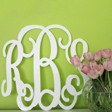 Monograms add the personal touch to a white wall with a vase of tulips.