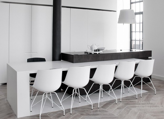 A white kitchen with black chairs and a wooden floor in a monochrome home.