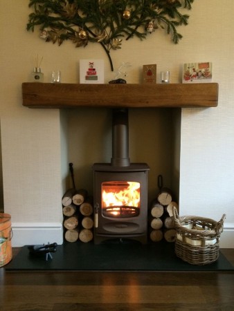 Traditional log burner with log storage in a disused fireplace (pinterest.com)