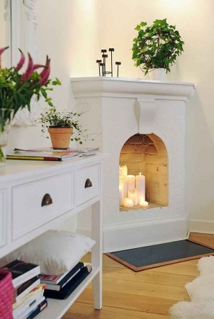 An adorable corner fireplace with oversized candles for effect (pinterest.com)