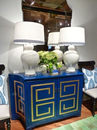 A blue dresser featuring Greek Key Design with two lamps and a mirror.