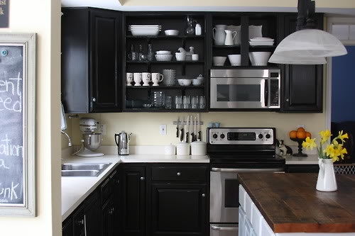 A kitchen with black cabinets and open shelving.