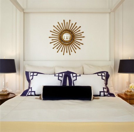 A white and blue bedroom with a Greek Key Design mirror.