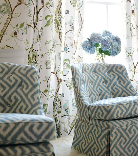Blue and white upholstered chairs with Greek key design in front of a window.
