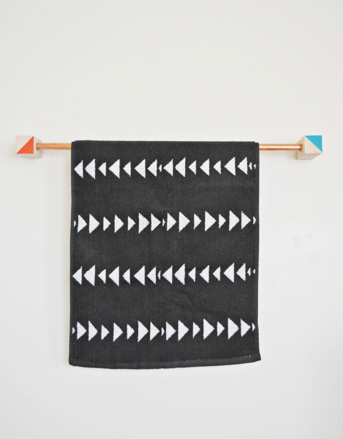 A black and white arrow towel hanging on a copper pipe.