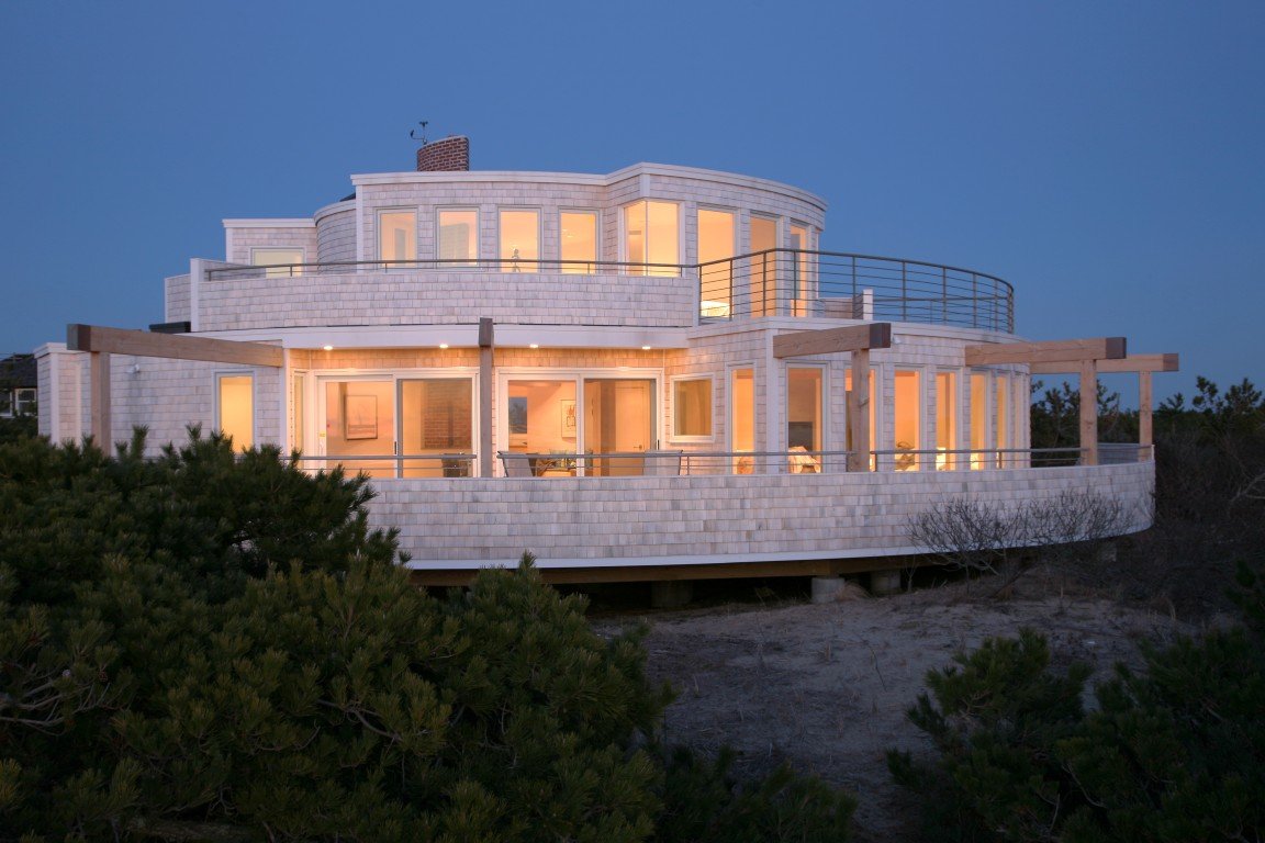 A circular white house on a sand dune at dusk.