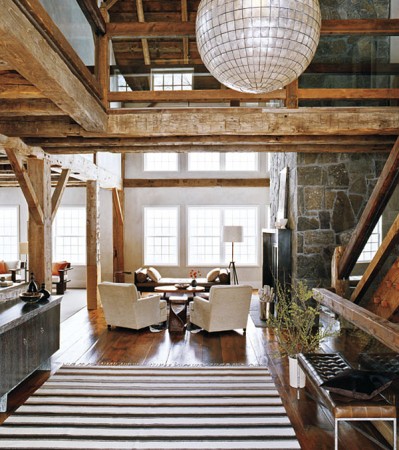 A living room with wood beams and a striped rug in an unconventional home.